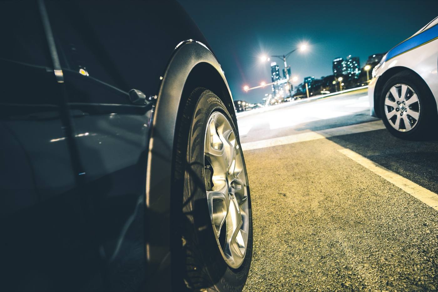 Car on a city street at night beside a police vehicle